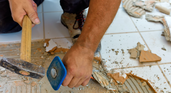 Handwerker entfernt mit Hammer und Meißel Bodenfliesen | © CRB Analyse Service GmbH